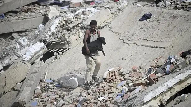 A man rescuing a dog in a ruin aftermath Venezuela earthquake